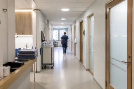 Illustrationsbild av vårdpersonal i blå arbetskläder i en ljus vårdkorridor