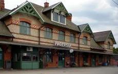 Fagersta stationsbyggnad med stationsskylt och klocka vid perrongen